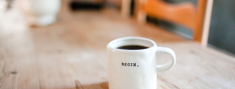 Cup of coffee printed with the word "begin" to mark the start of a positive morning